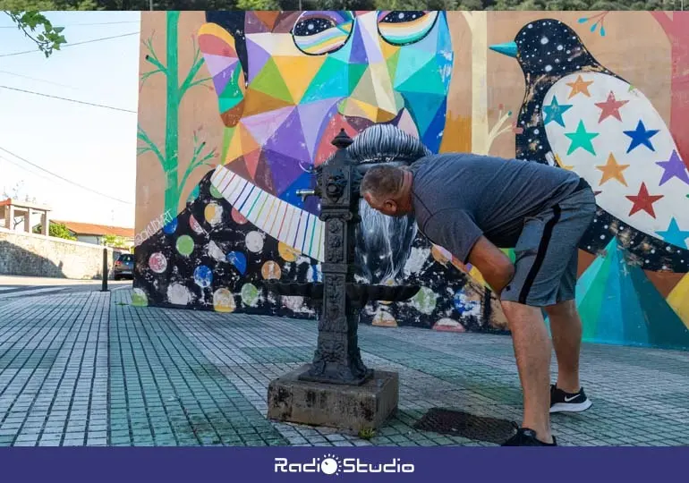 Un vecino de Polanco bebe agua en la fuente p&uacute;blica situada junto al mural de Okuda | Foto: Ayuntamiento