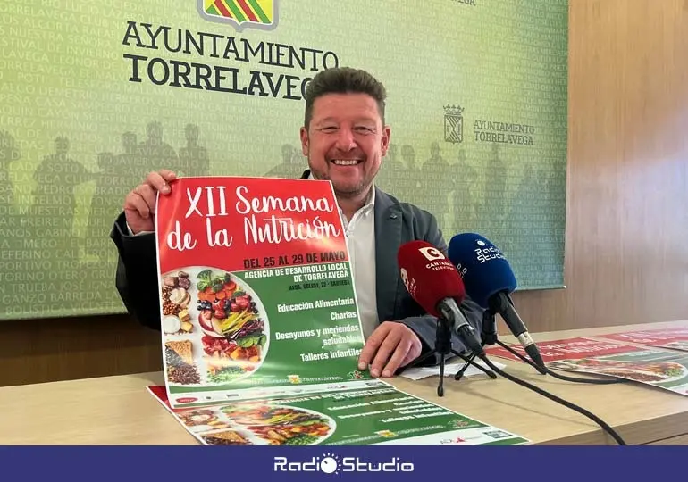 Jes&uacute;s S&aacute;nchez posa con el cartel de la XII Semana de la Nutrici&oacute;n de Torrelavega | Foto: Radio Studio