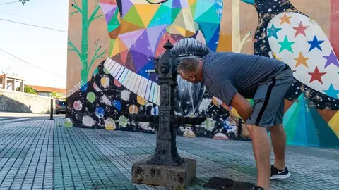 Un vecino de Polanco bebe agua en la fuente p&uacute;blica situada junto al mural de Okuda | Foto: Ayuntamiento